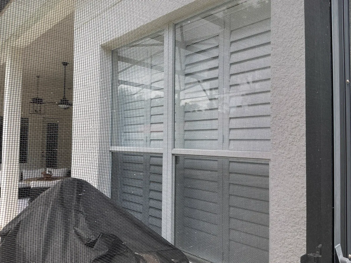 A black-framed sliding glass door with its screen, opening to a covered patio.